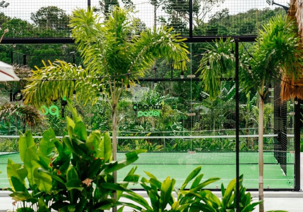 Lush greenery and palm trees surround an outdoor padel court at Bantai Padel in Koh Samui, Thailand