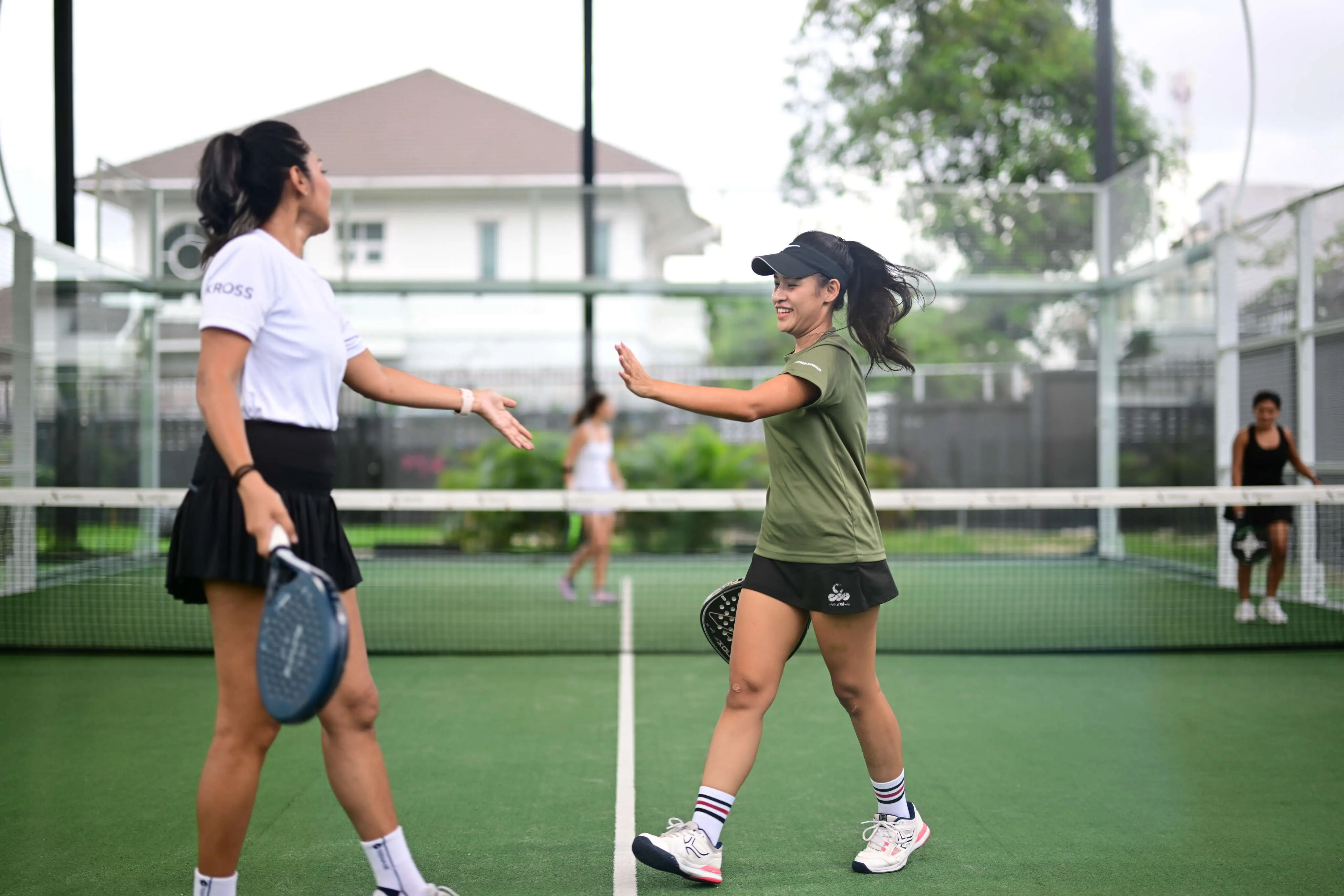 Two female padel players shaking hands amicably over the net after a competitive game.
