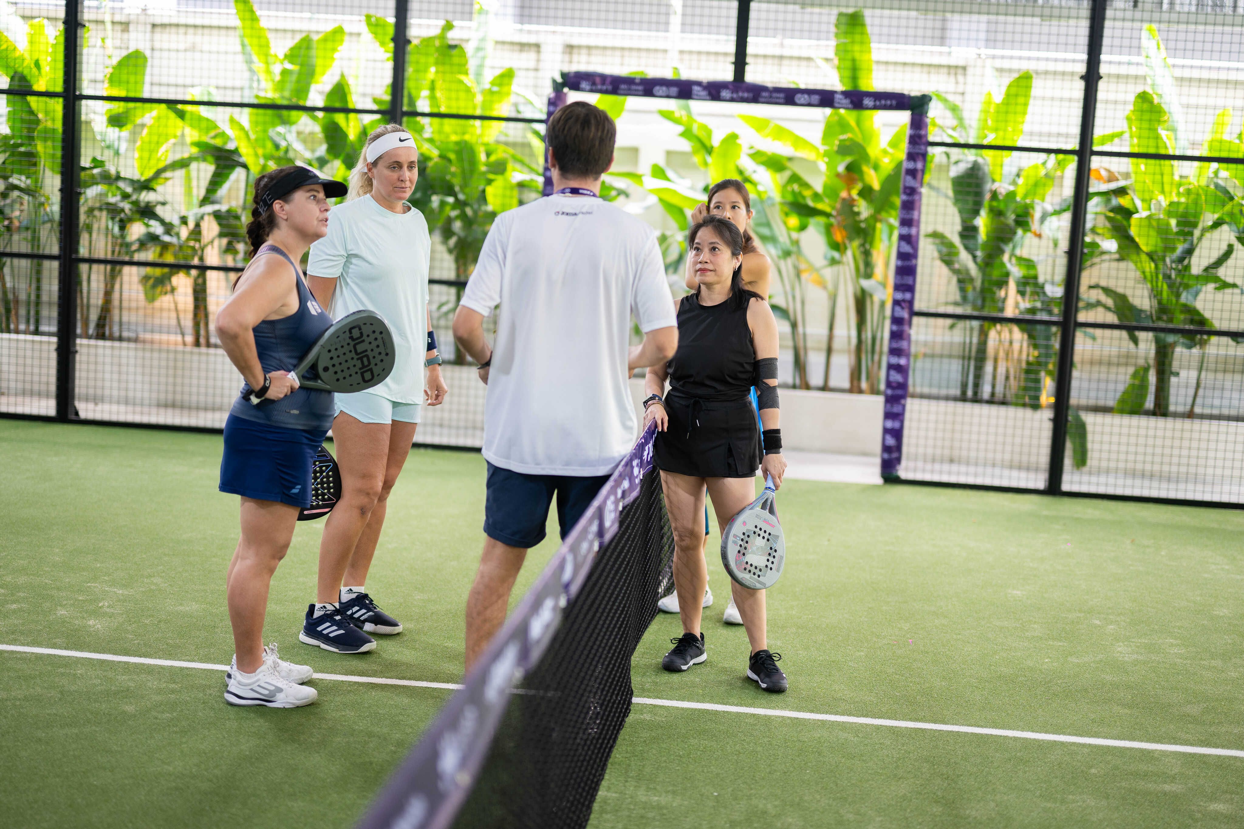 Coach instructing padel players on court
