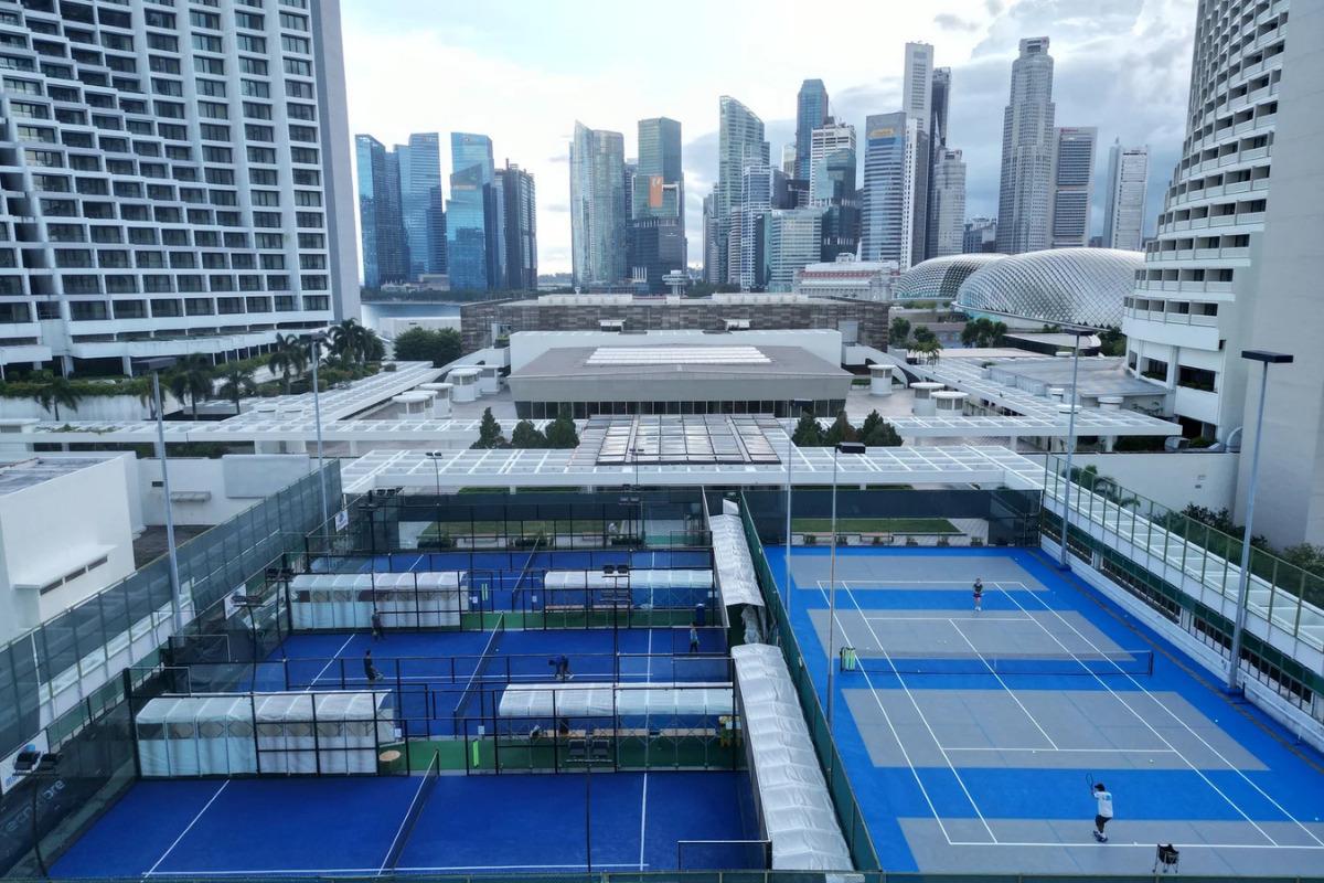 Rooftop padel and tennis courts at MBP Sports in Marina Square, Singapore, with the city skyline in the background and players in the courts.