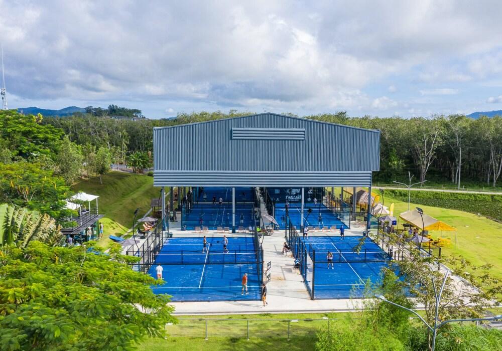 Players on multiple blue courts surrounded by greenery at Padel Phuket Blue Tree in Phuket, Thailand