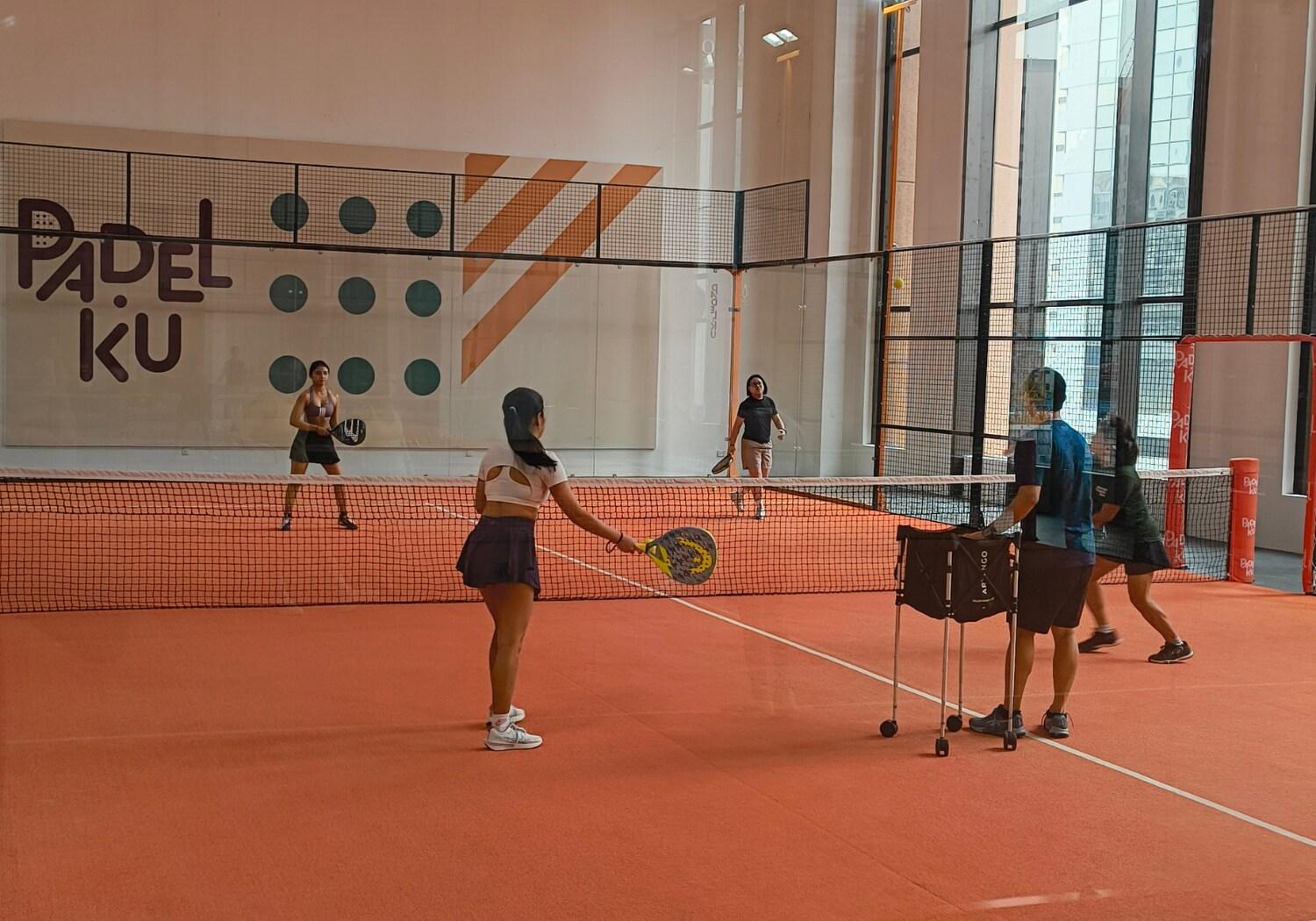 Indoor padel court at PadelKu Berjaya Times Square with players training on an orange court