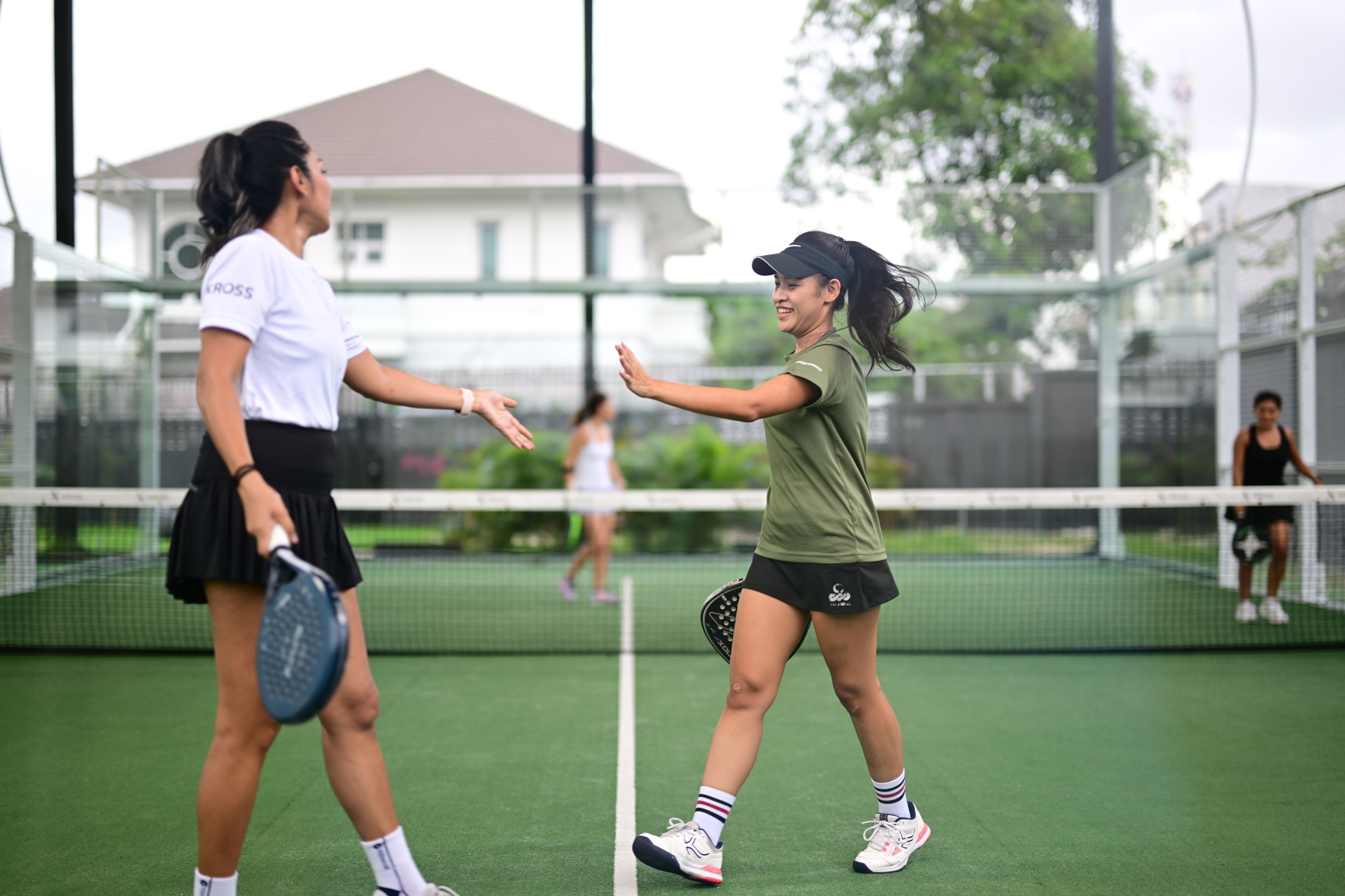 Two women shaking hands on a padel court