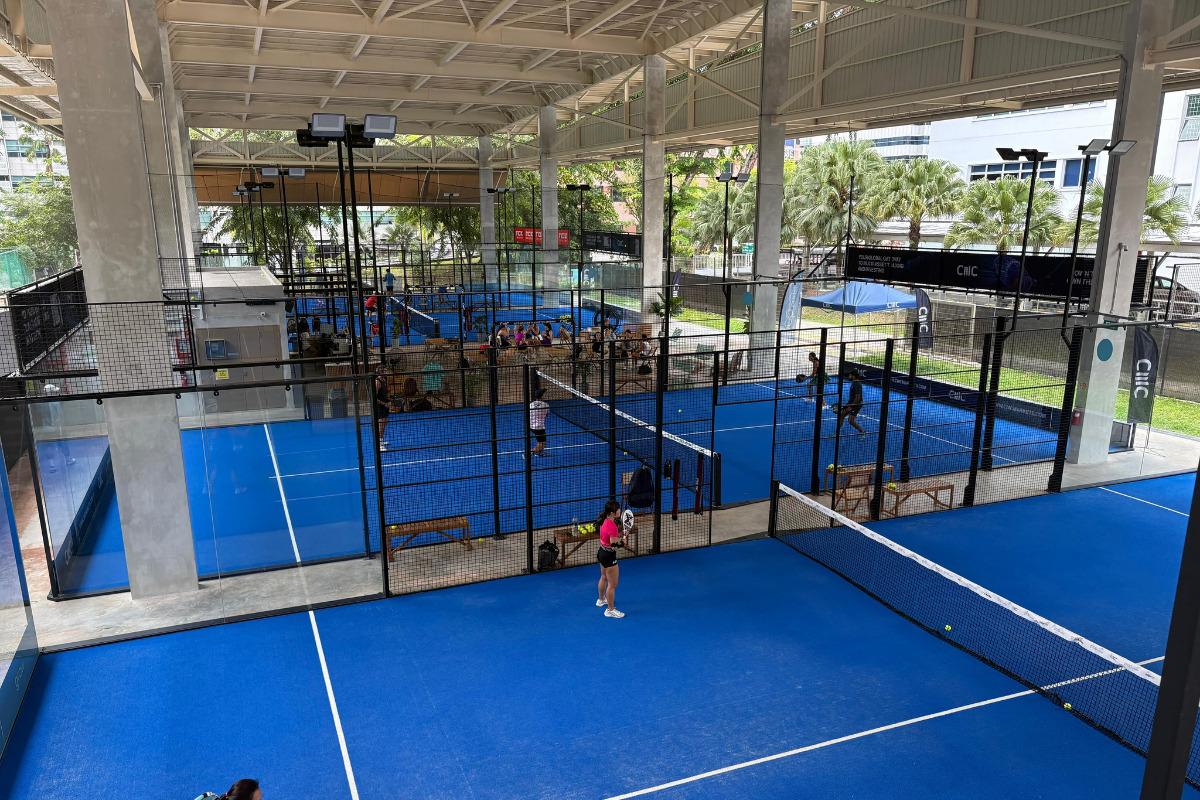 Blue indoor padel courts at Pop Padel in Singapore, with players practicing on the courts