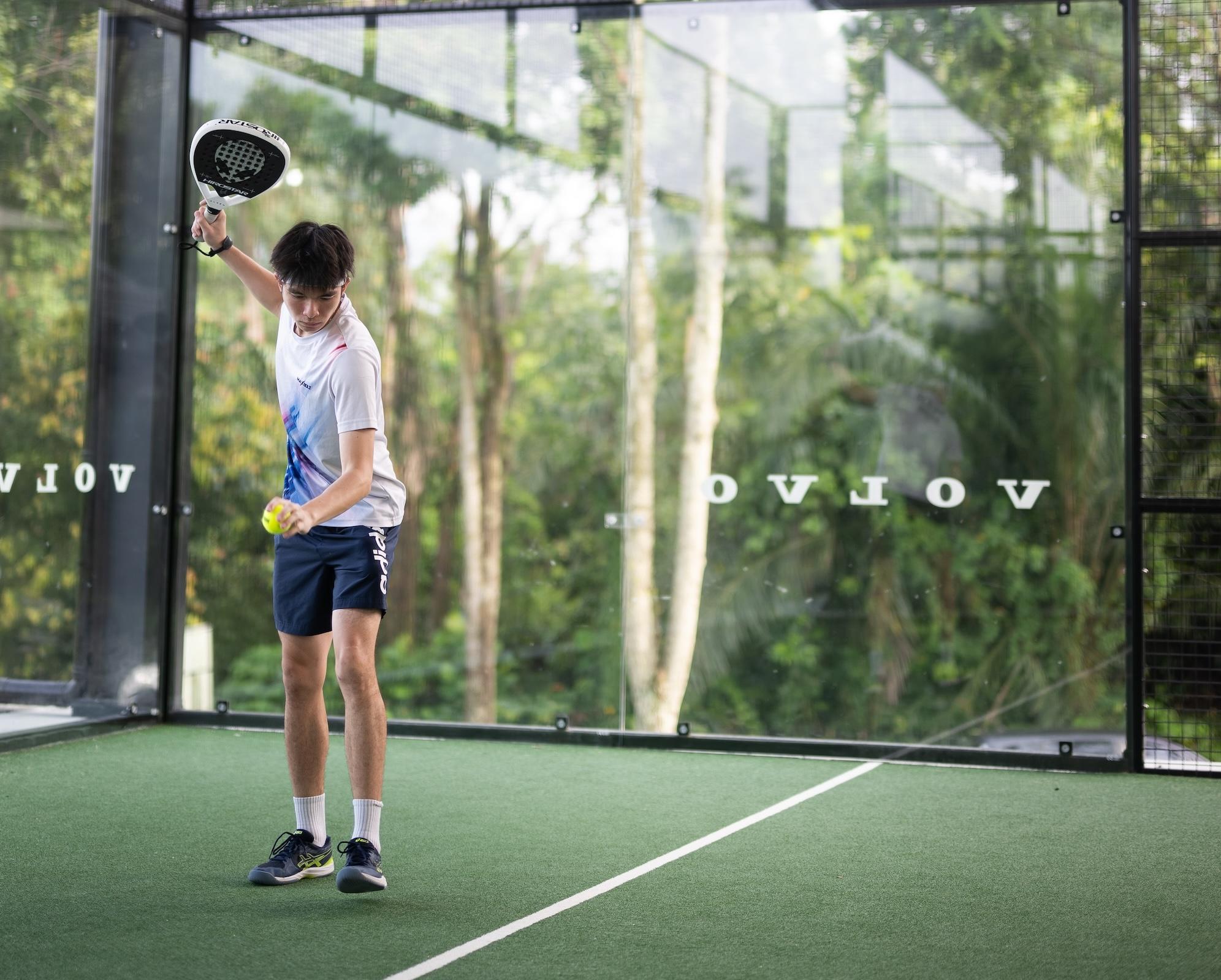 A man standing on a padel court preparing to serve