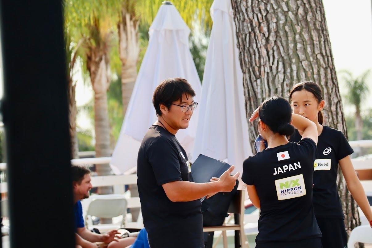 Tom Jack discussing tactics with two Japanese national team padel players.